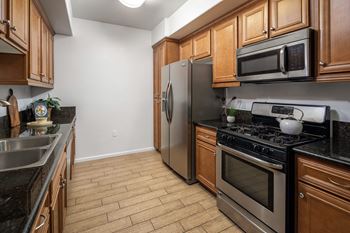 a kitchen with stainless steel appliances and wooden cabinets at Le Blanc Apartment Homes, Canoga Park